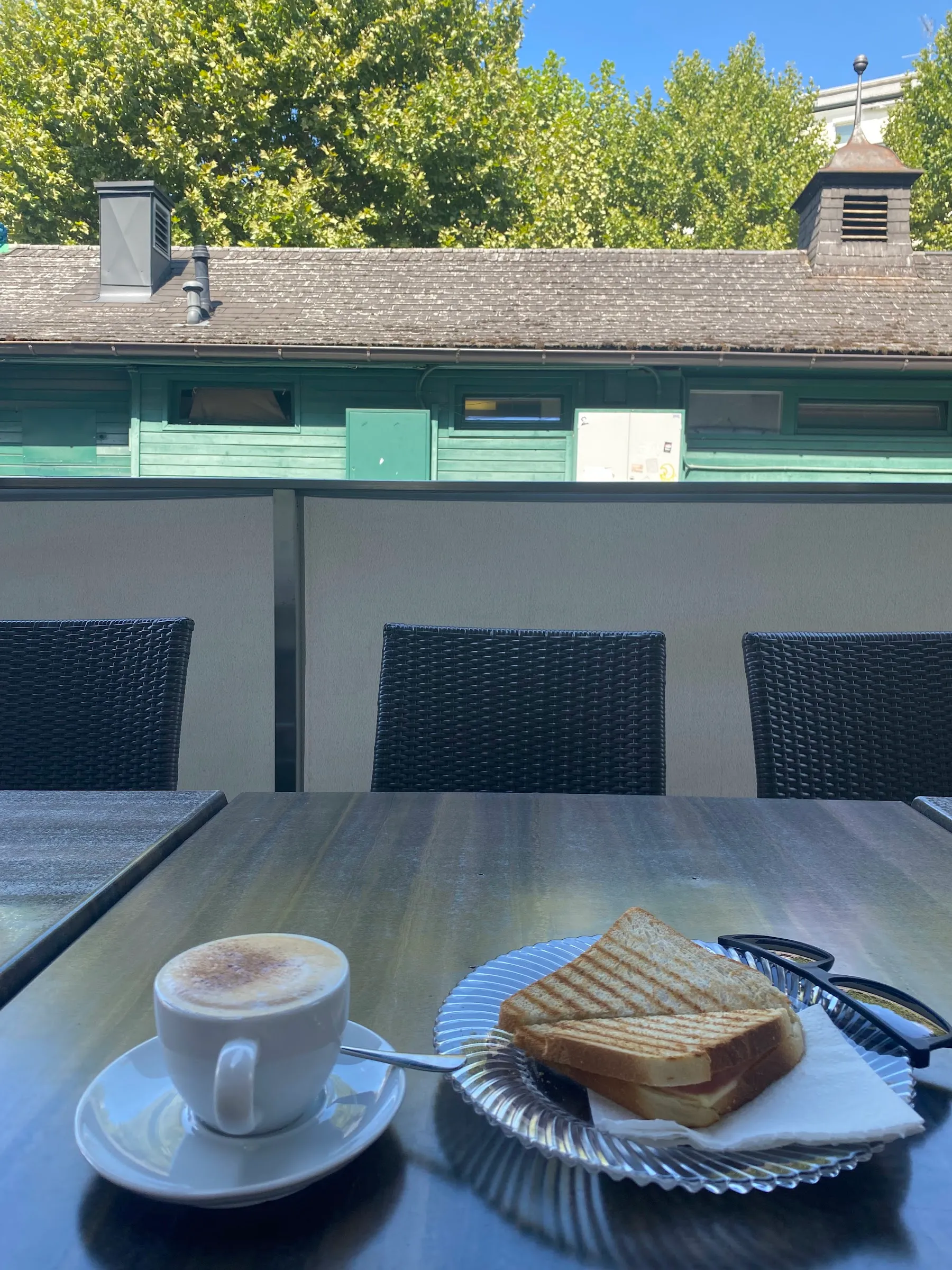 Cappuccino und Toast auf der Terrasse, dahinter Bäume